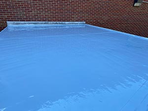 Roof-Restoration-Kettering-OH-Ohio-2 | A.H. Sturgill Roofing Blue tarp covering a flat surface, with a red brick wall in the background.